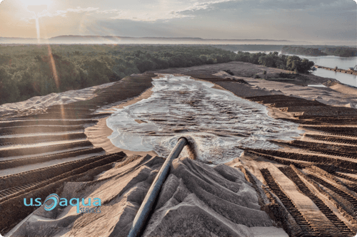 A large dredging vessel on a beach, dredging sand onto the coast, while two men stand by and watch, services and equipment rentals provided by U.S. Aqua Services, your leader in dredging services  (4) (1)