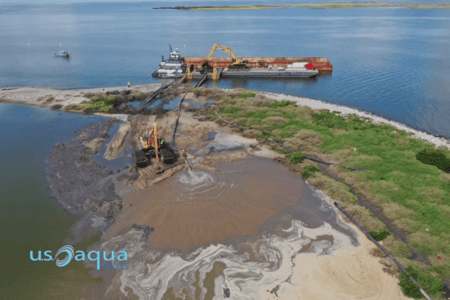 a large boat with a suction dredger pulling sediment off of a work site with a yellow backhoe, rented from US Aqua  (1)