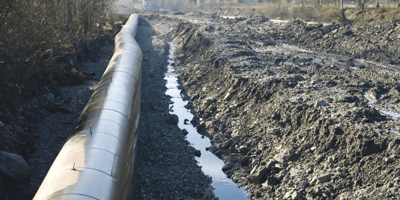 A large oilfield pipe in a trench dug by dredging equipment supplied by US Aqua