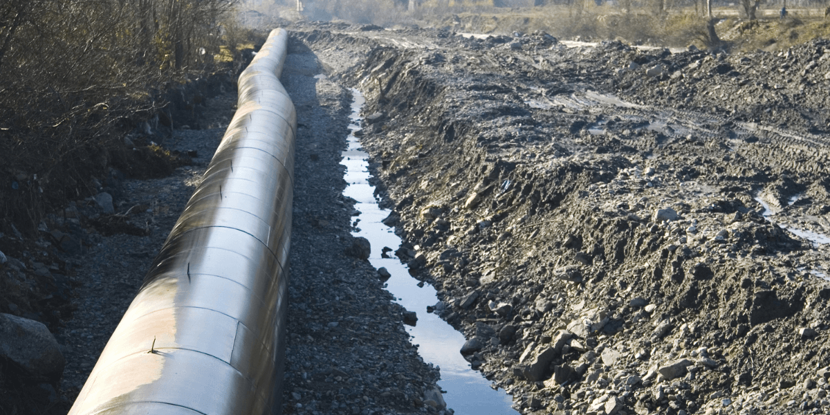 A large oilfield pipe in a trench dug by dredging equipment supplied by US Aqua
