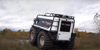 A white fat truck driving through a marshy landscape