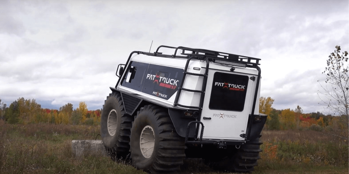A white fat truck driving through a marshy landscape