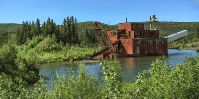 An old school dredging station in a small body of water in the middle of the mountains used for gold dredging.
