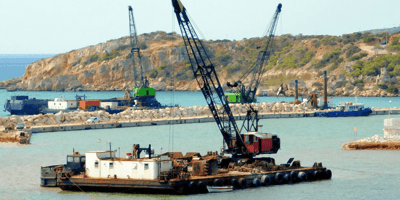 a large dredging barge in a harbor with heavy equipment on it.