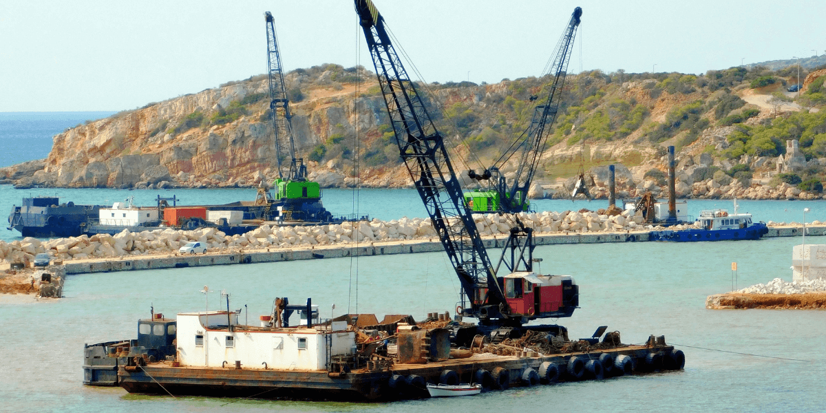 a large dredging barge in a harbor with heavy equipment on it.