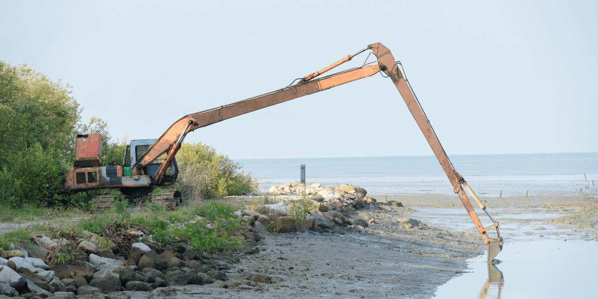 A large excavator in the marsh dredging a waterway.