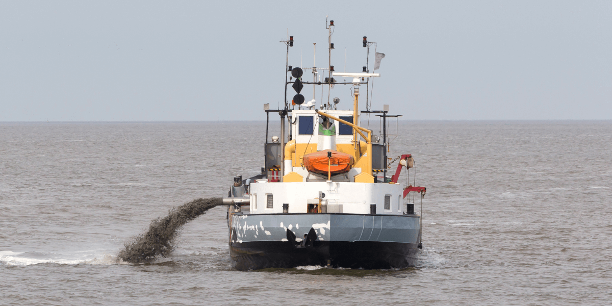 A large dredging ship using jetting equipment to blast sediment in a large body of water.